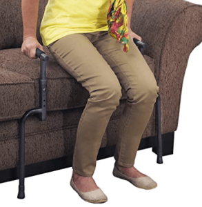 A senior using a standing cane to stand up from a couch